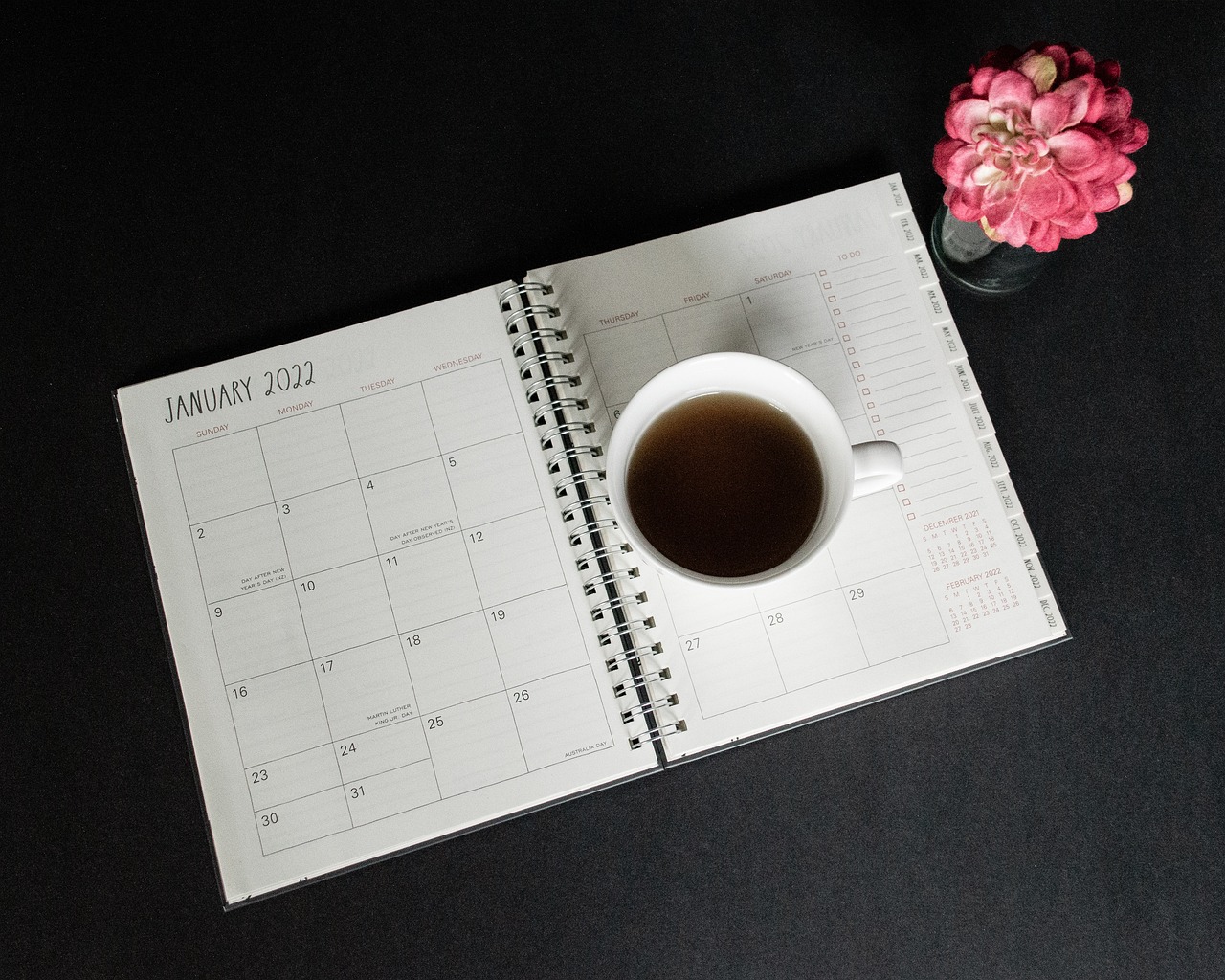 Kalenderbuch 2022 darauf eine Tasse Kaffee abgestellt mit Blumenvase rechts daneben