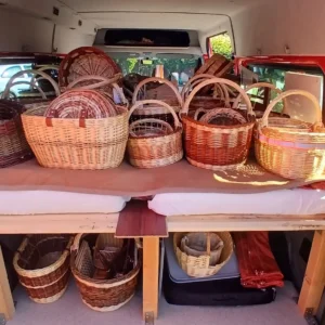 Der Innenraum eines roten Transporters ist bis oben hin mit geflochtenen Weidenkörben in verschiedenen Größen und Brauntönen beladen, die auf einem eingebauten Holzbett stehen.