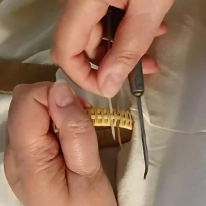 Hände bei der filigranen Flechtarbeit mit Weidenschienen an einem hellen Armband