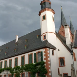 Ein gepflasterter Vorplatz mit Bierzeltgarnituren vor einem alten Klostergebäude bei aufziehendem Unwetter.