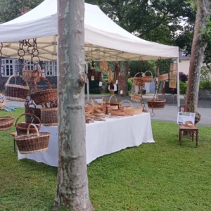 Marktstand zwischen zwei Bäume auf Wiese mit Korbwaren
