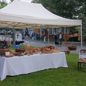 Bauernmarkt Juni 2026 vor dem Kurhaus-Hotel Marktstand zwischen zwei Bäume auf Wiese mit Korbwaren